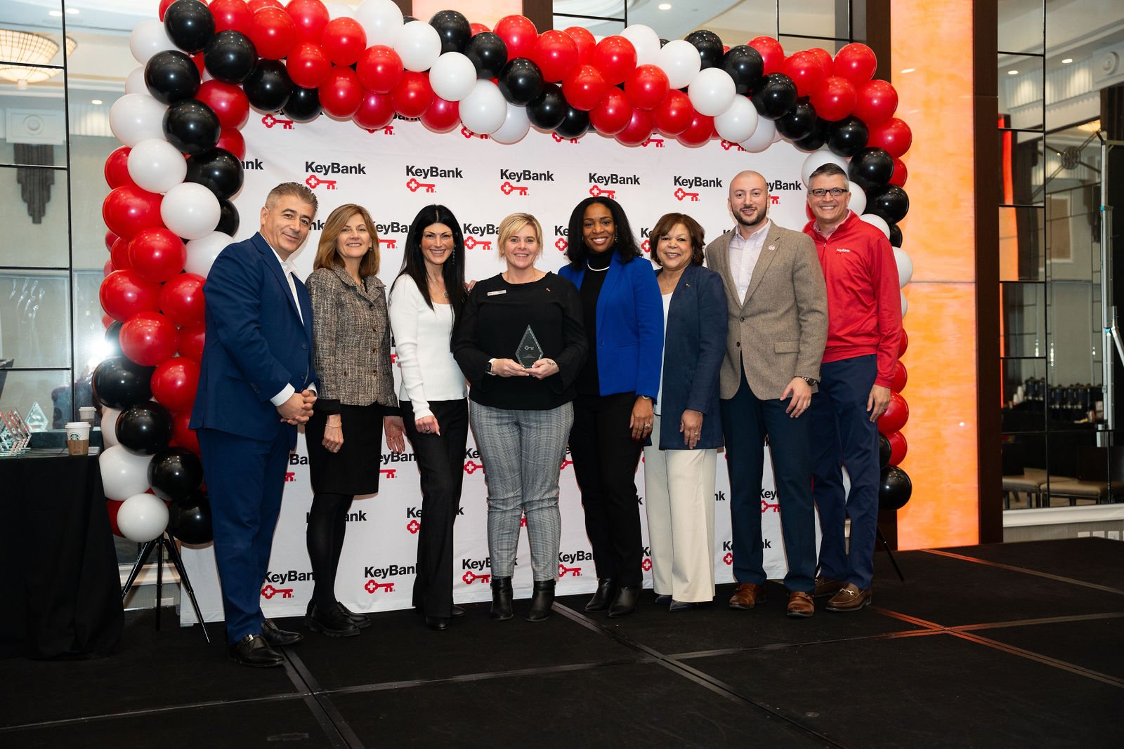 A KeyBank team poses beneath red, white and black balloons at an awards event