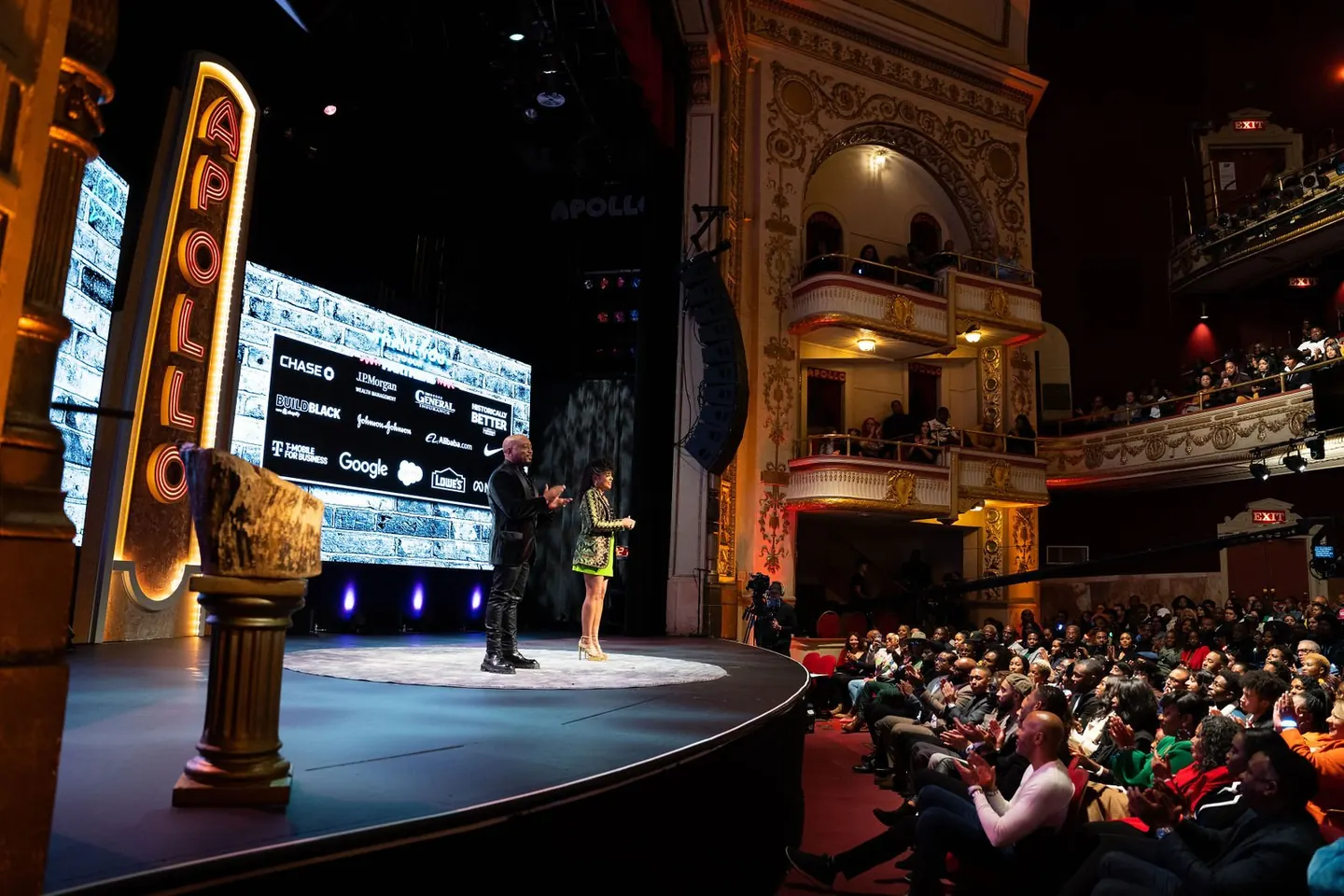 Two presenters address an audience at the Apollo Theater